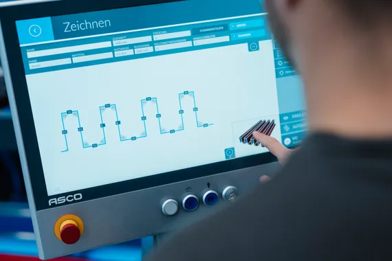 Mitarbeiter bedient die Variobend V-Touch Maschinensoftware am Touchscreen mit grafischer Darstellung mehrerer Blechprofile.