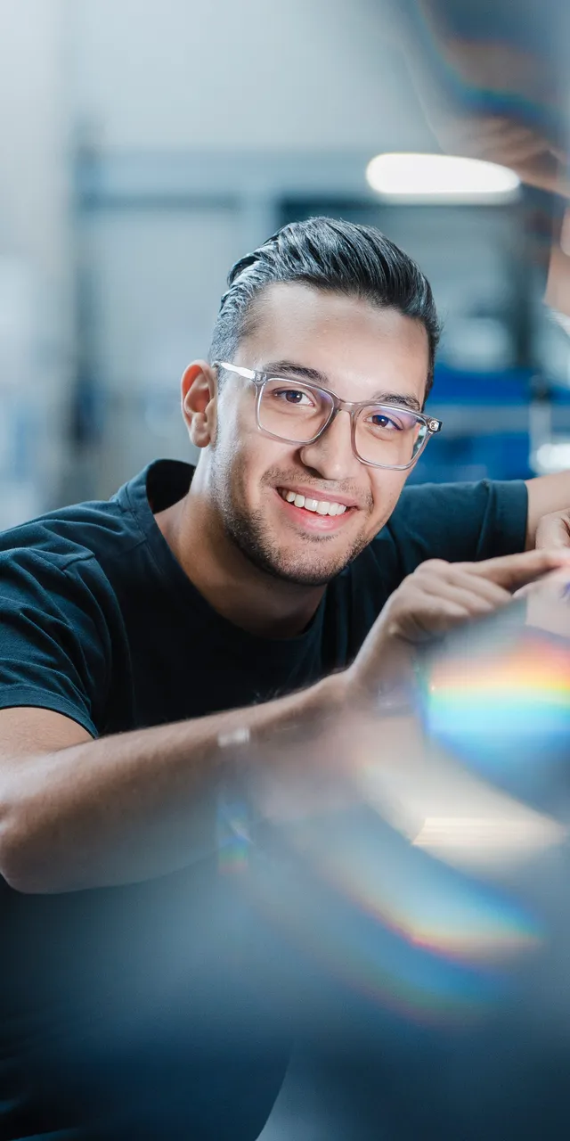 Lächelnder Mitarbeiter der ASCO Machinery Group bei der Montage einer Blechbearbeitungsmaschine in der Produktionshalle.