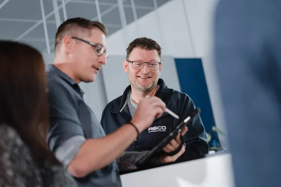 Mitarbeiter der ASCO Machinery Group im fachlichen Austausch über ein technisches Bauteil in der Serviceabteilung.