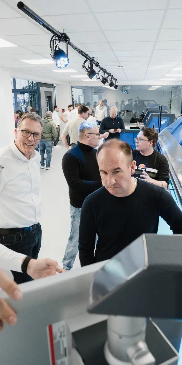 Besucher der ASCO Machinery Group Experience Days begutachten gemeinsam eine Blechbearbeitungsmaschine während der Hausmesse.