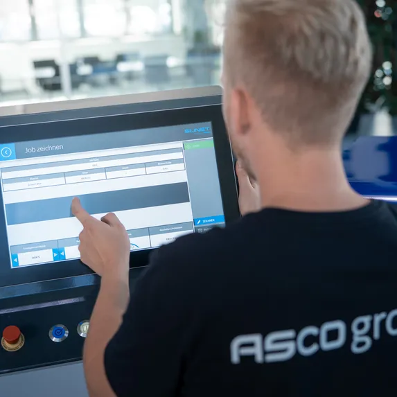 Mitarbeiter der ASCO Machinery Group bei der Bedienung der Slinet S-Touch Maschinensteuerung über ein Touchdisplay.