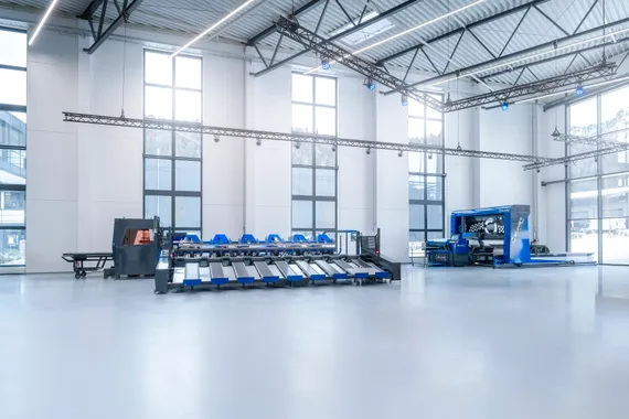 Gesamtansicht einer automatisierten Fertigungslinie mit Variobend Biegemaschine und Slinet Blechzuschnittanlage in einer Produktionshalle.