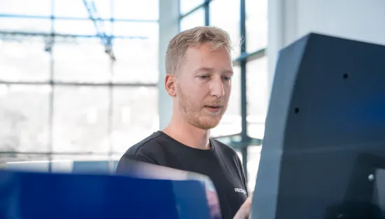 Mitarbeiter bei der Bedienung der Slinet S-Touch Maschinensoftware an einem Bildschirm einer Blechbearbeitungsanlage.