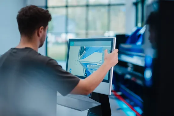 Mitarbeiter bedient die Variobend V-Touch Maschinensteuerung am Touchscreen einer Biegemaschine mit grafischer Darstellung eines Blechprofils.