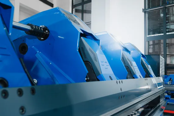Detailaufnahme des vollelektrischen Variobend V2.5 Doppelbiegers mit blauem Maschinengehäuse und mechanischen Komponenten des Biegesystems.