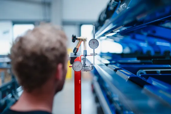 Mitarbeiter der ASCO Machinery Group bei der Präzisionsmessung mit einer Messuhr an einer Blechbearbeitungsmaschine.
