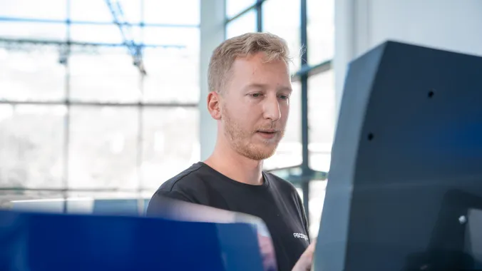 Mitarbeiter bei der Bedienung der Slinet S-Touch Maschinensoftware an einem Bildschirm einer Blechbearbeitungsanlage.