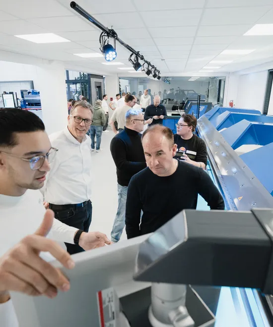 Besucher der ASCO Machinery Group Experience Days begutachten gemeinsam eine Blechbearbeitungsmaschine während der Hausmesse.