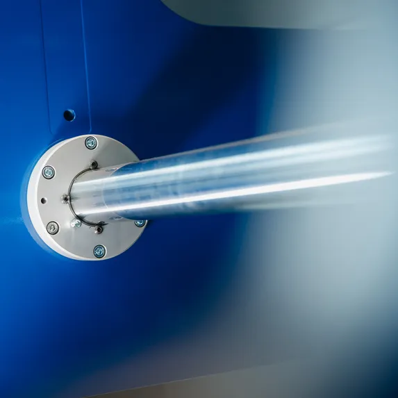Detailaufnahme der metallischen Steuerwelle eines Variobend Einfachbiegers mit rundem Befestigungsflansch am blauen Maschinengehäuse.