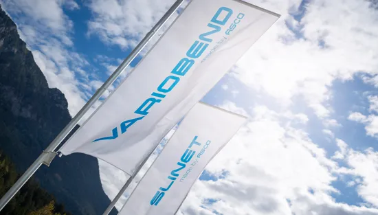 Firmenfahnen der ASCO Machinery Group mit Variobend und Slinet Markenlogos vor einer Bergkulisse in Bischofswiesen.